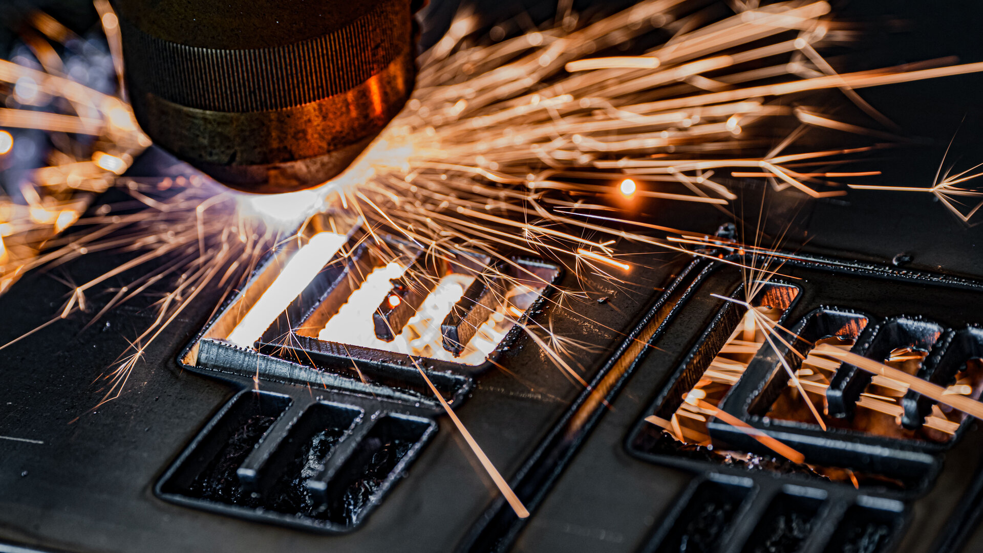 Intensive Funken sprühen aus einer Maschine, die Metall bearbeitet, wobei klare Konturen der geschnittenen Teile sichtbar sind.