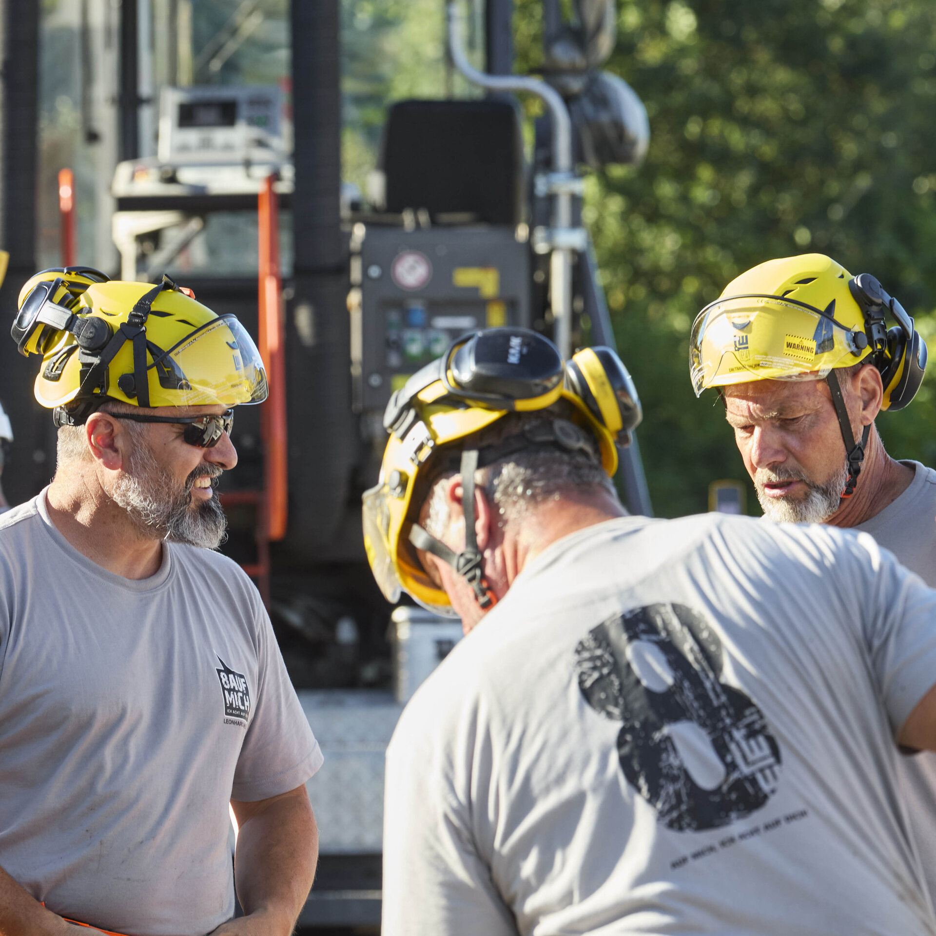 Die Gruppe von Arbeitern trägt Schutzhelme und zeigt eine engagierte Teamarbeit in einer sonnigen Umgebung.