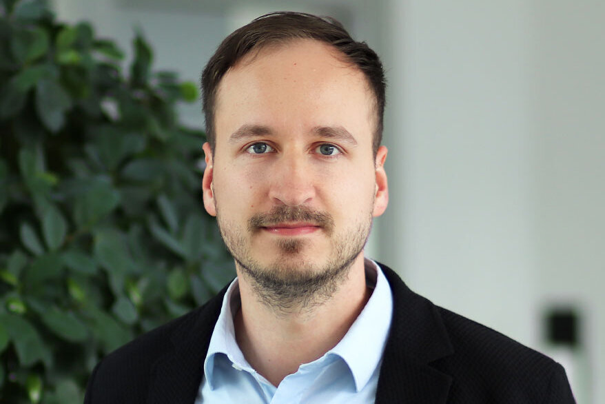 Ein Mann in einem Anzug steht neben einer großen Pflanze.