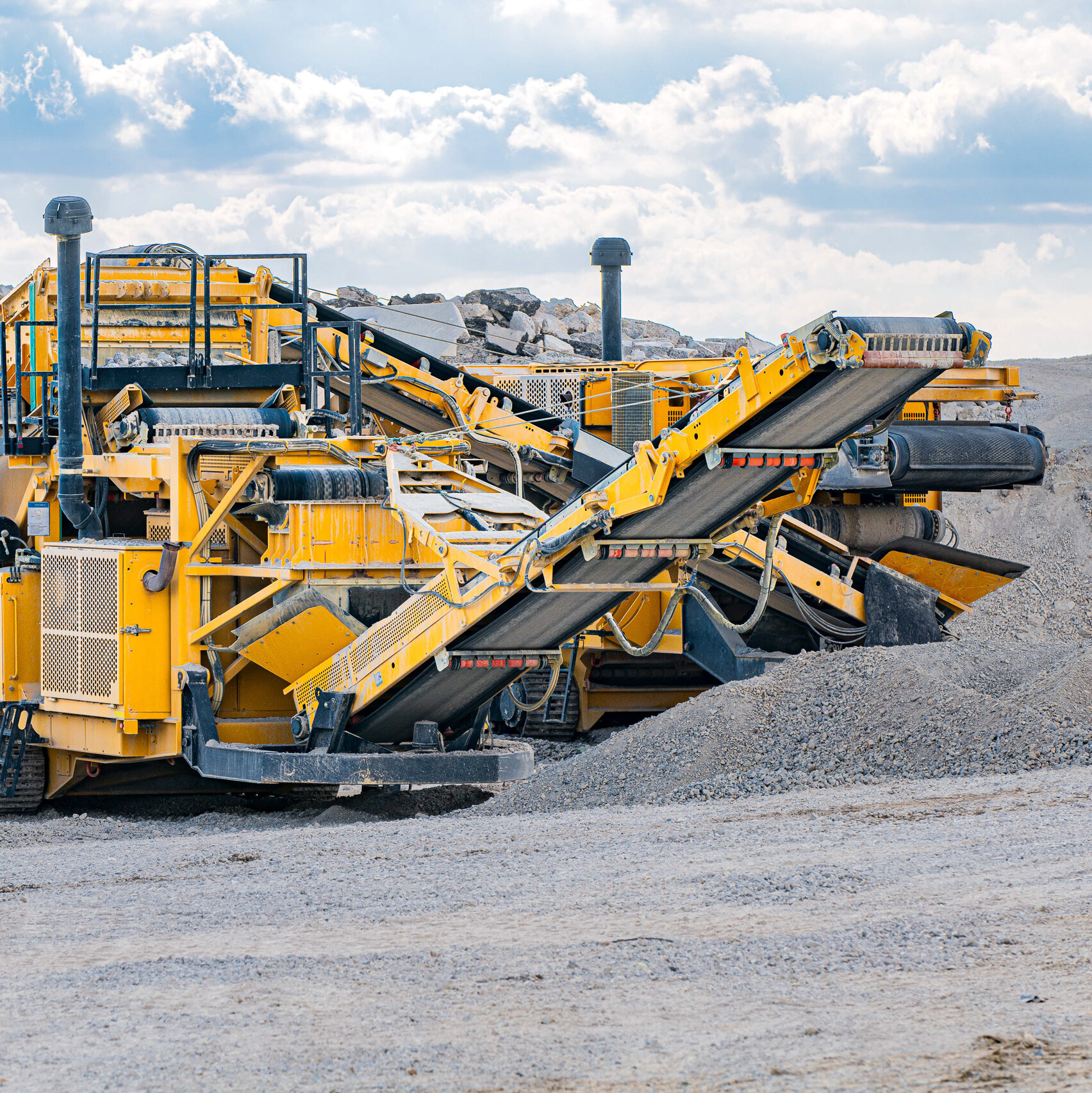 Die Maschine mit Förderbändern und Treppen ist in einem Steinbruch positioniert, bereit, Material zu verarbeiten.