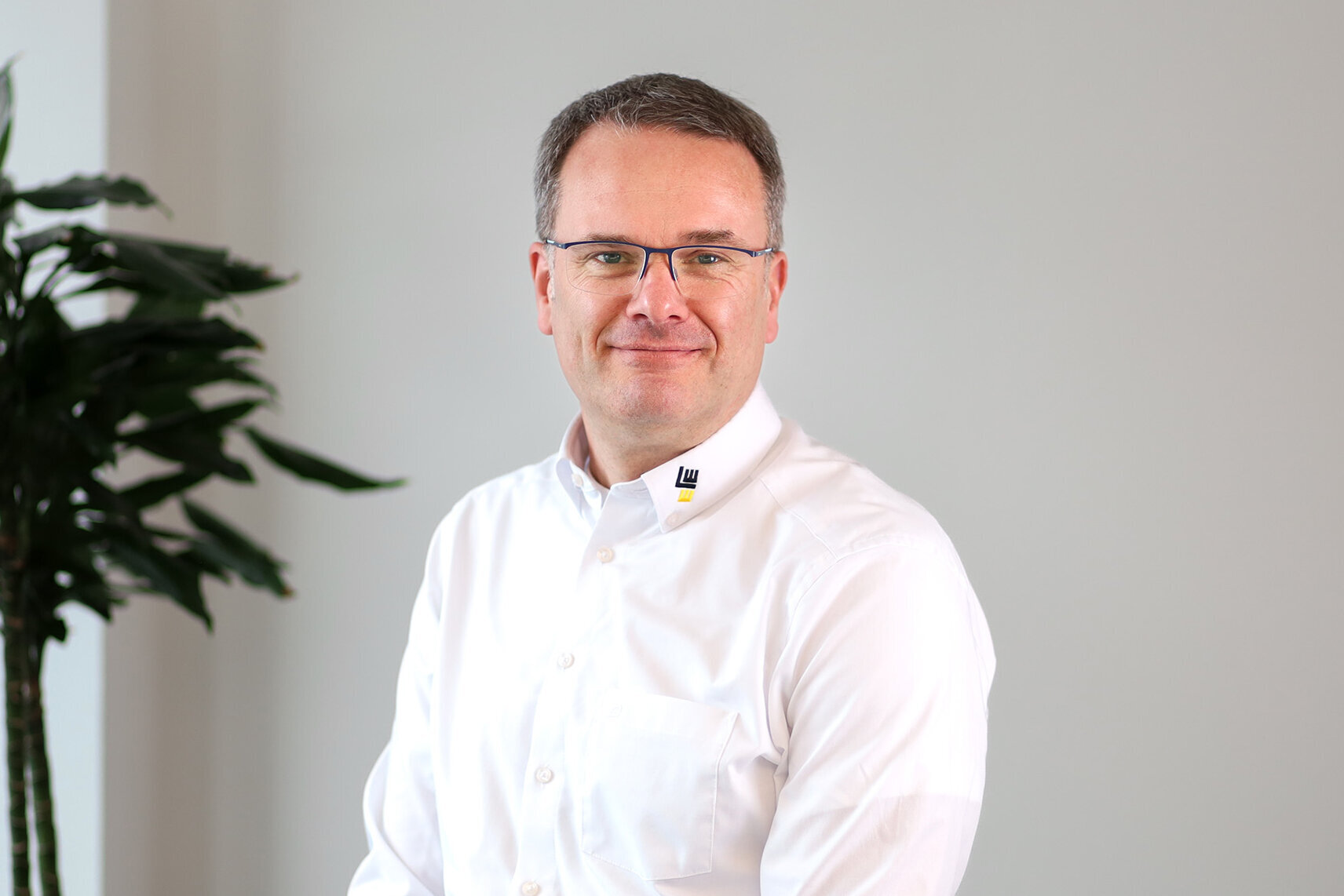 Ein Mann mit Brille trägt ein weißes Hemd.